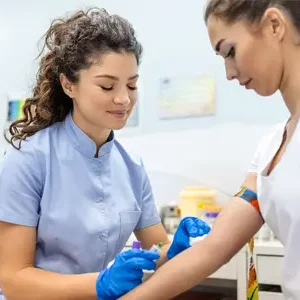 female phlebotomist drawing blood from female patient