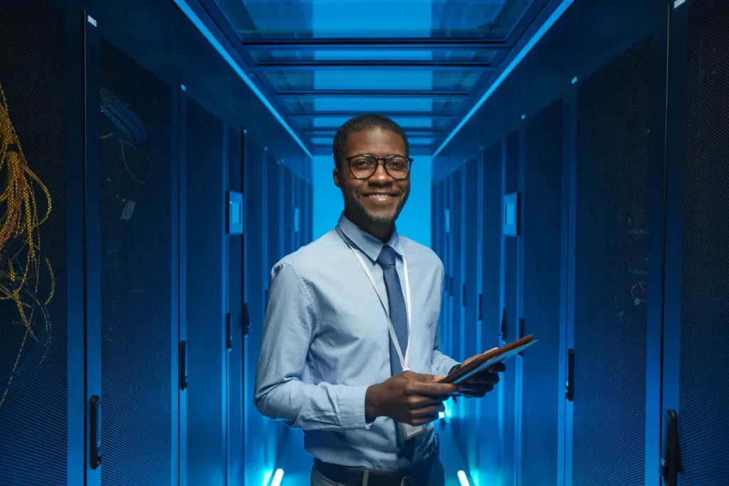 black male IT tech smiling at camera in a server room