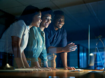 Shot of a group of young businesspeople using a computer together during a late night at work